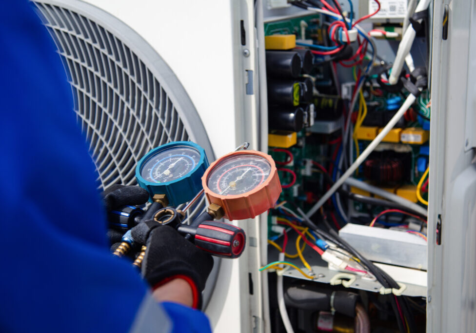 Air conditioner service .The air conditioner technician is using a gauge to measure the refrigerant pressure. air compressor.